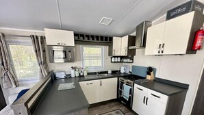 Una cocina compacta con microondas, estufa, lavaplatos y armarios.