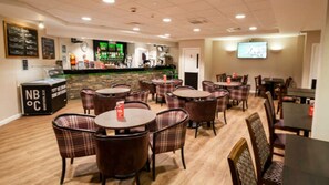 A restaurant with round tables and chairs, a bar area, and a television screen. - Caravan - Sleeps 4 - Pool - Pet Friendly (Ringwood)