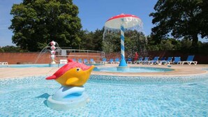 Una piscina con un elemento acuático, que incluye una fuente y un paraguas grande.