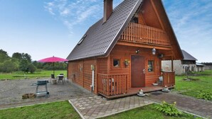 Une cabane en bois avec un toit en pente, un porche à l’avant et une petite terrasse.