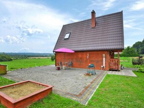 A wooden house with a tiled roof, a patio with outdoor furniture, and a fenced garden area. - Cottage in the Countryside, Quiet, Private Garden (Malechowo)