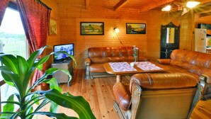 L’intérieur d’un chalet en bois chaleureux et accueillant, avec des meubles en cuir, un téléviseur et des œuvres d’art accrochées aux murs.