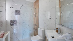 A modern bathroom with a glass shower enclosure, a toilet, a sink with a mirror, and a hairdryer. - Casa Loresa Silver (Orihuela)
