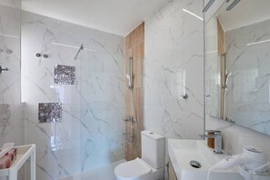 A modern bathroom with a glass shower enclosure, a toilet, a sink with a mirror, and a hairdryer. - Casa Loresa Silver (Orihuela)