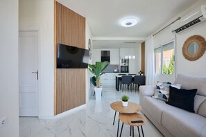A modern living room with a sofa, a coffee table, and a TV mounted on a wooden panel. - Casa Loresa Silver (Orihuela)