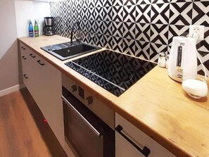 A kitchen with a black and white patterned backsplash, a built-in stove, a coffee maker, and a white appliance on the counter. - 4-bedroom Holiday Home With Sauna and Whirlpool (Mielno)