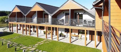 A modern building with multiple balconies, a covered outdoor area, and a stone pathway.