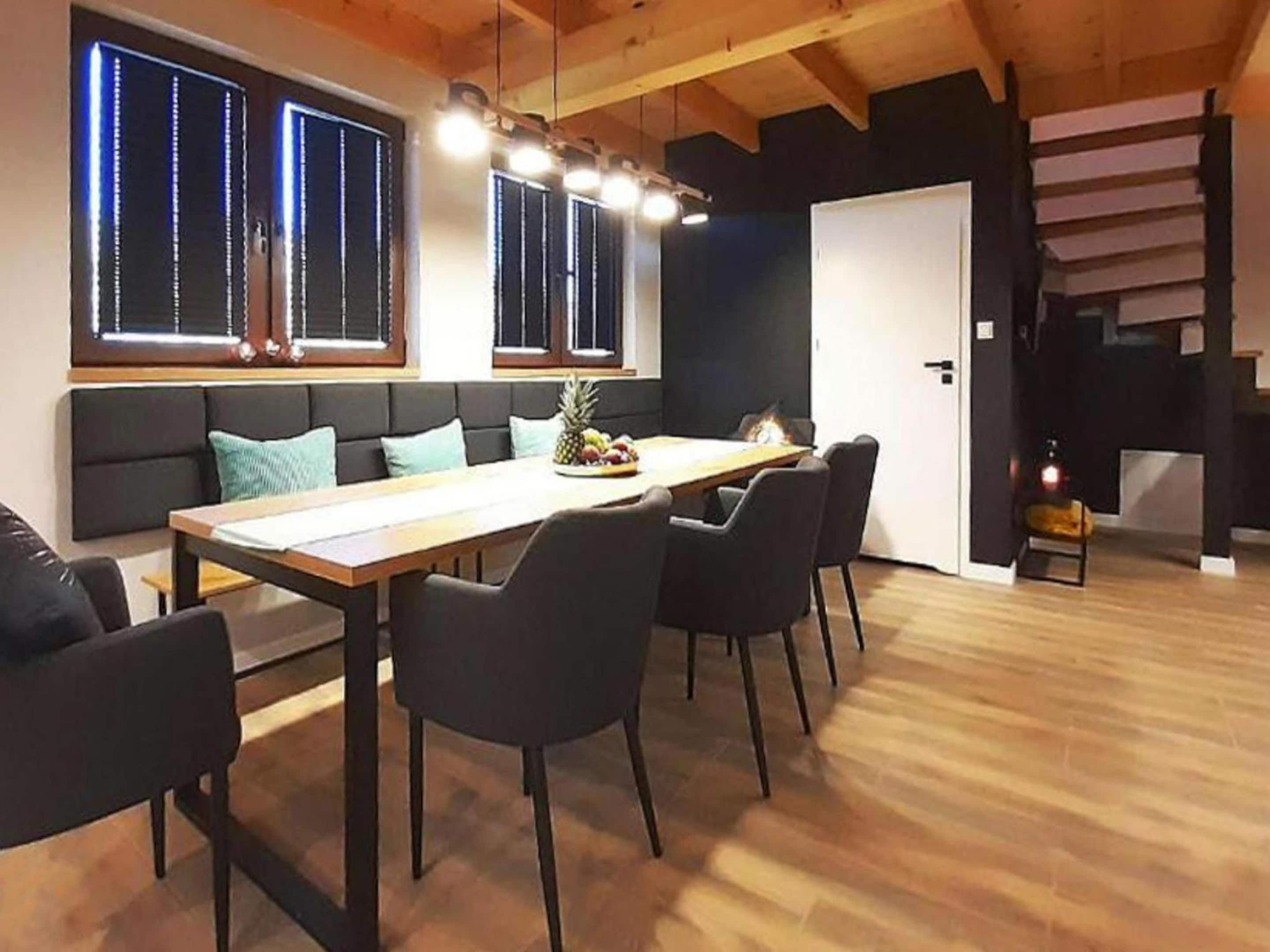 Un comedor moderno con una mesa de madera, sillas negras y un banco con cojines.