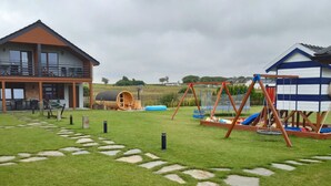 Il s’agit d’une propriété résidentielle comprenant une grande maison, un espace de jeux avec une balançoire et un petit abri de jardin.