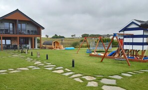 A residential property with a large house, a play area with a swing set, and a small shed.