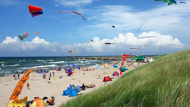Une plage où l’on peut admirer des cerfs-volants colorés et des tentes.