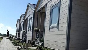 Une rangée de cabanes modernes, de plain-pied, dotées de grandes fenêtres et d’un toit plat.