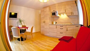 Un espacio habitable compacto con cocina, comedor y un sofá rojo.