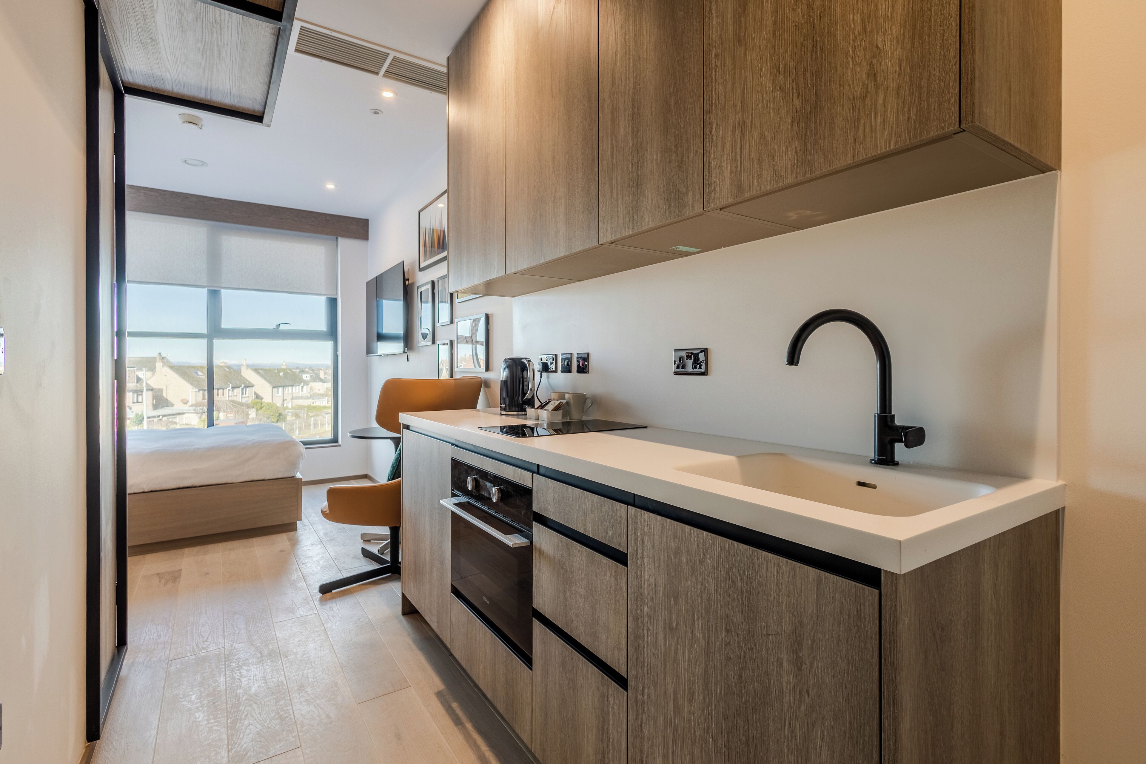 A modern kitchen with a large window, a built-in oven, and a sleek black faucet.