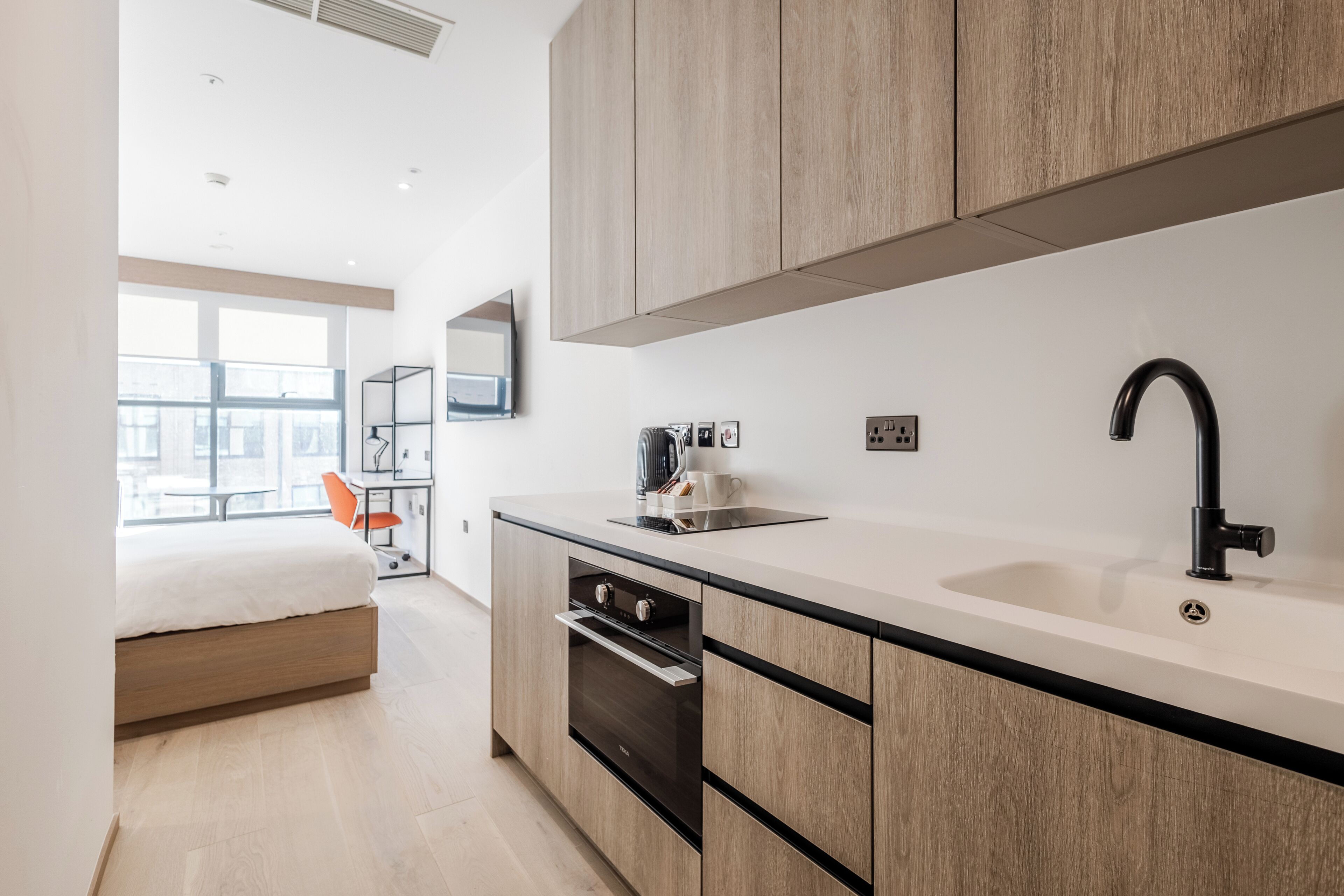 A modern kitchen with wooden cabinets, a black faucet, and a built-in oven.