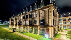 A multi-story building with a brick facade, large windows, and a well-lit exterior. - THE SPACE TO STAY APARTHOTEL (St. Andrews)