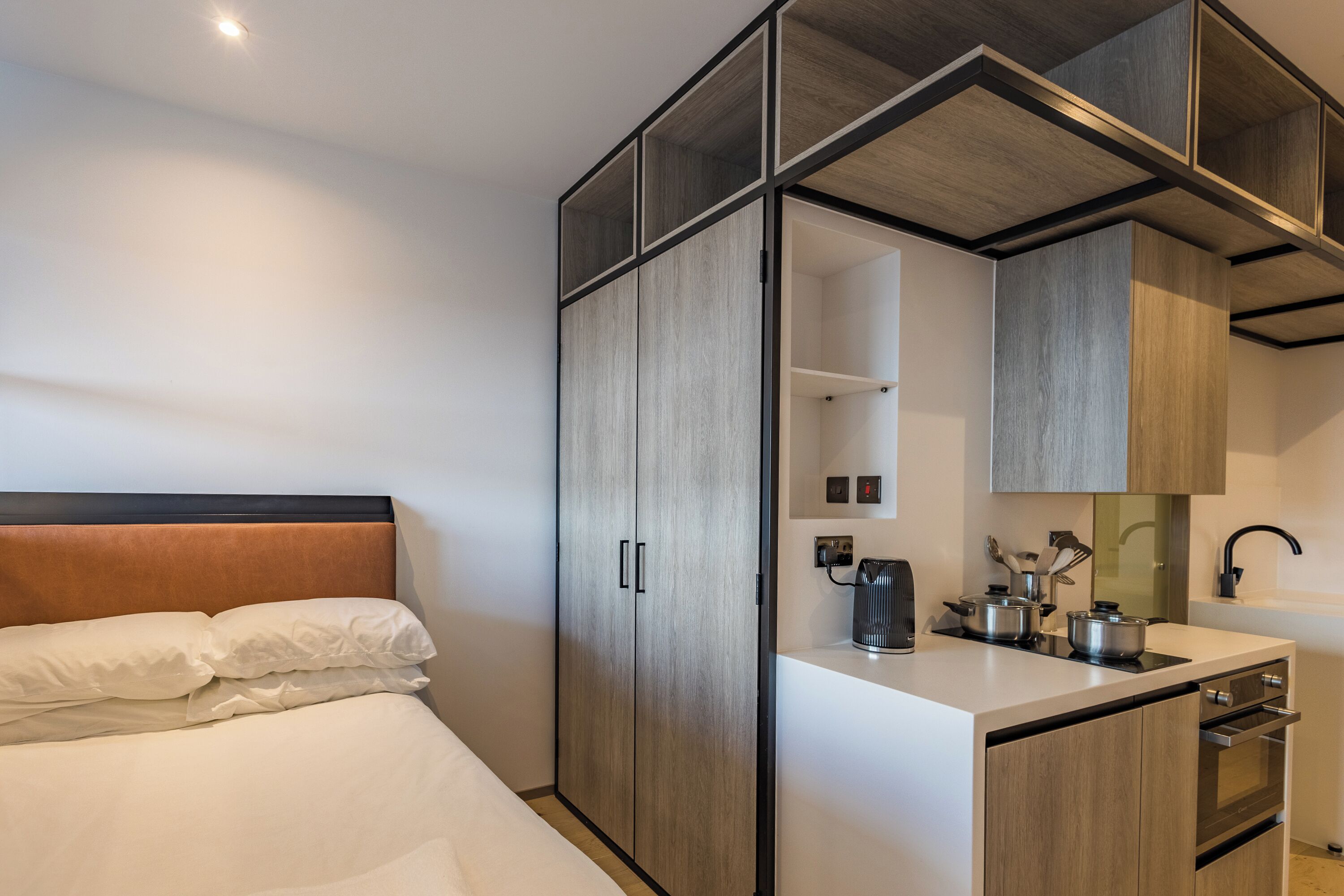 Et moderne hotelværelse med seng, tekøkken og et garderobeskab med spejl.