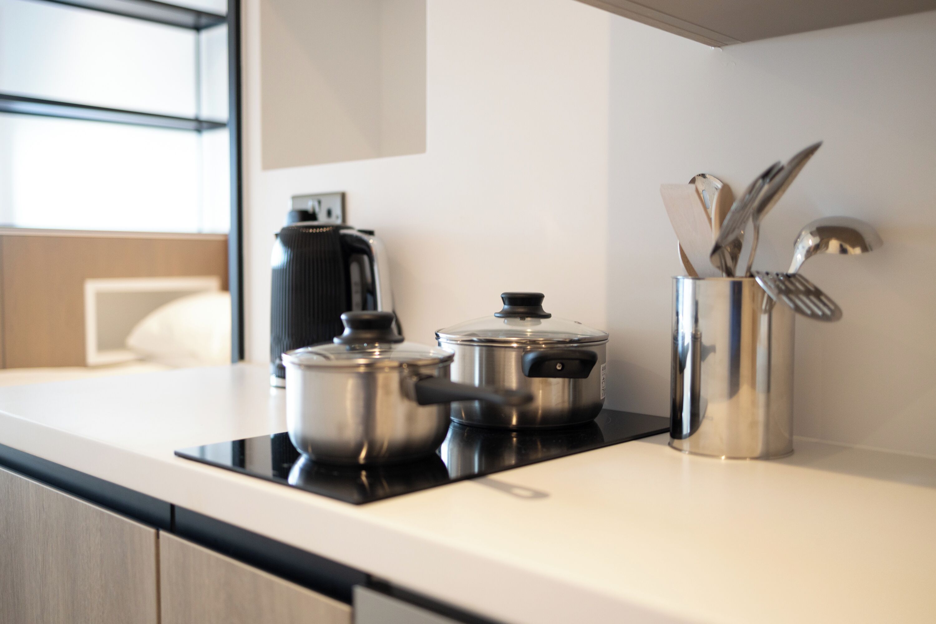 Une cuisine moderne équipée d’appareils électroménagers en acier inoxydable, d’une machine à café et d’ustensiles de cuisine posés sur le plan de travail.