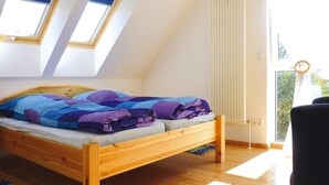 A bedroom with a wooden bed, a sloped ceiling, and two skylights. - Ferienhaus Zum Roten Adler in Storkow (Storkow)