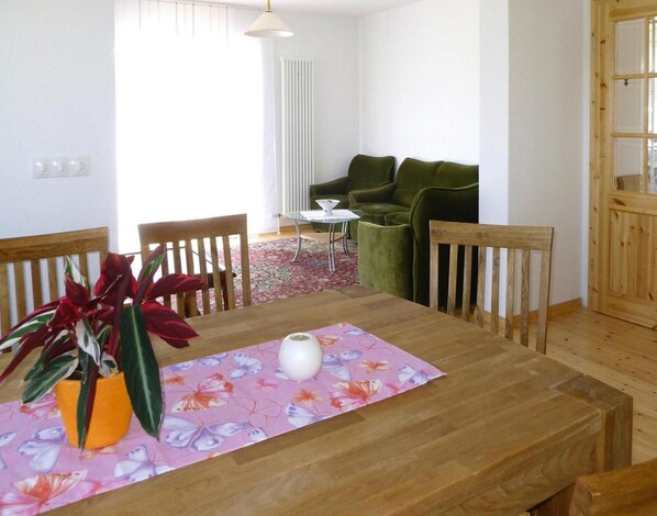 Un coin repas avec une table en bois, des chaises, un vase et une plante en pot.