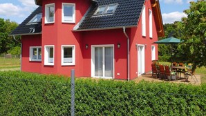 A red two-story house with a dark roof, white windows, and a small balcony. - Ferienhaus Zum Roten Adler in Storkow (Storkow)