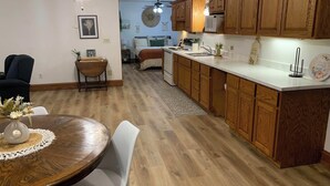 Eine moderne Küche mit Holzschränken, ein Essbereich mit rundem Tisch und Deckenventilator.