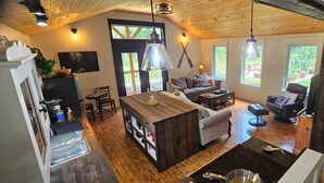 Una sala acogedora con techo de madera, una isla central con cubierta de vidrio, un sofá y un sillón de masaje.