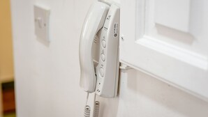 A white telephone mounted on a wall.