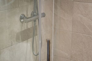 A shower with a handheld showerhead and a fixed wall-mounted faucet. - Muttoes Apartments (No 21) (St Andrews)