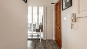 A hallway with a wooden door, a framed picture, and a telephone on the wall.
