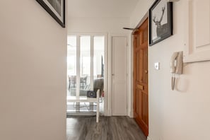 A hallway with a wooden door, a framed picture, and a telephone on the wall. - Muttoes Apartments (No 21) (St Andrews)