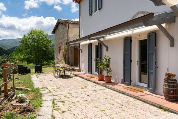 A courtyard with a table and chairs, potted plants, and a wooden barrel. - Country House / Farm House in Gricignano with 2 bedrooms sleeps 6 (Gricignano)