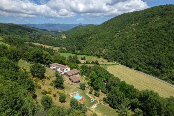 Una casa con piscina rodeada de vegetación exuberante y colinas.