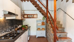 A kitchen with a gas stove, white cabinets, and a wooden staircase leading to a loft area.