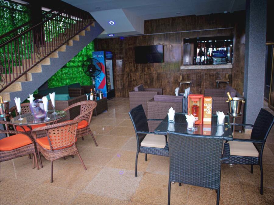 A lobby with a staircase, wicker furniture, a bar area, and a television screen.