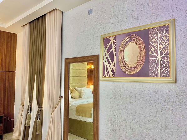 A room with a bed, a mirror, and a wall-mounted artwork. - Prince Xclusive Royale Hotels (Awka)