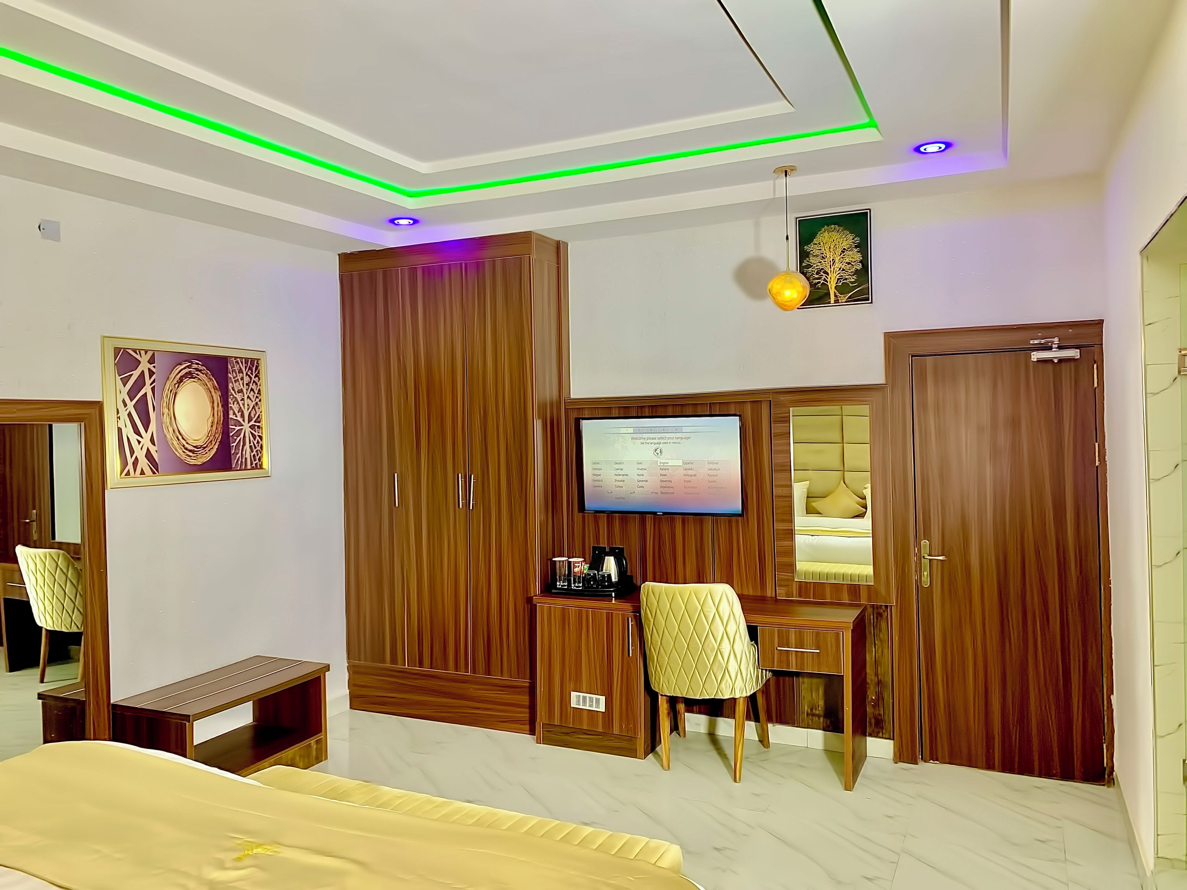 Habitación de hotel con cama, escritorio con silla, armario, televisión y un adorno decorativo en la pared.