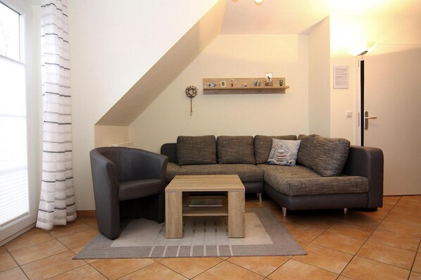 A living room with a sectional sofa, a small coffee table, and a wall-mounted shelf. - Apartment, Zingst (Zingst)