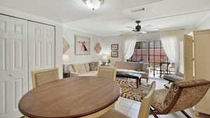 Amplia sala de estar con una mesa redonda de madera, sofás color beige y un ventilador de techo.