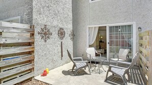 Un patio con dos sillas, una mesa, cerca de madera y suelo de hormigón.