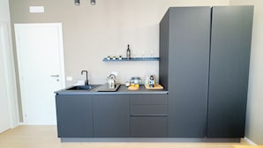 Una cocina moderna con un lavamanos, hervidor y estante con utensilios de cocina.