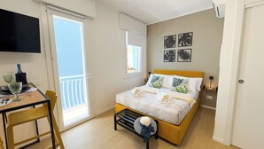 Un dormitorio con cama, escritorio, silla, ventana y puerta.