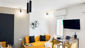 Una sala de estar moderna con un sofá, una mesa de comedor y un televisor montado en la pared.