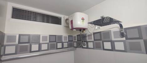 A bathroom with a shower, a water heater, and a ventilation system.