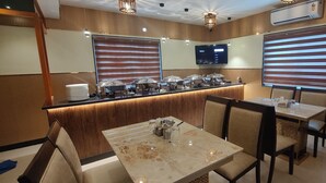 Una sala ristorante con un'area buffet, una TV a parete e una zona con tavoli e sedie.