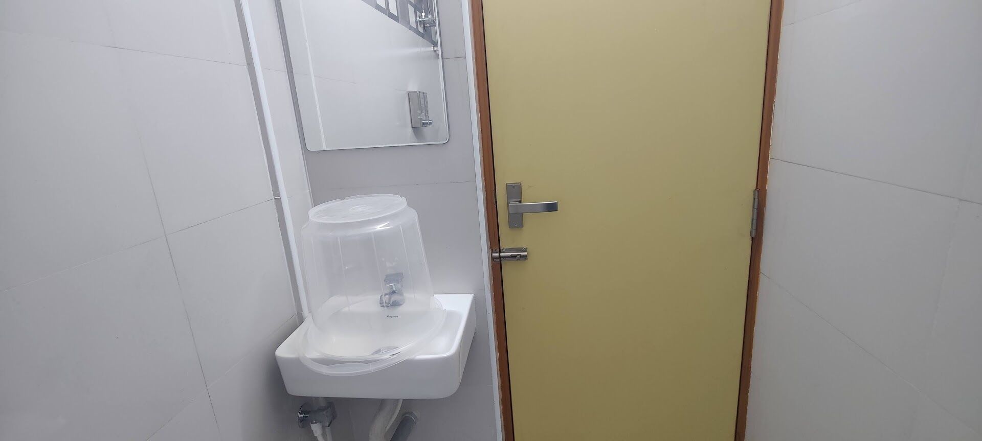 Een badkamer met een wit wastafel, een spiegel en een gele deur.