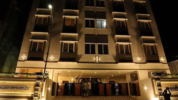 Un hotel a più piani con un ingresso centrale, una facciata ben illuminata e un cartello all'altezza del piano terra.