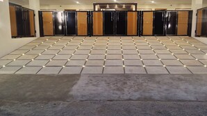 Un'hall d'albergo con pavimento piastrellato, una reception e una serie di porte nere e in legno.