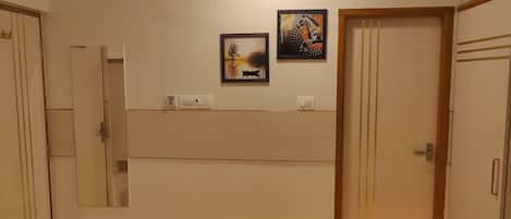 Habitación de hotel con un espejo grande, una puerta de madera y dos obras de arte enmarcadas en la pared.
