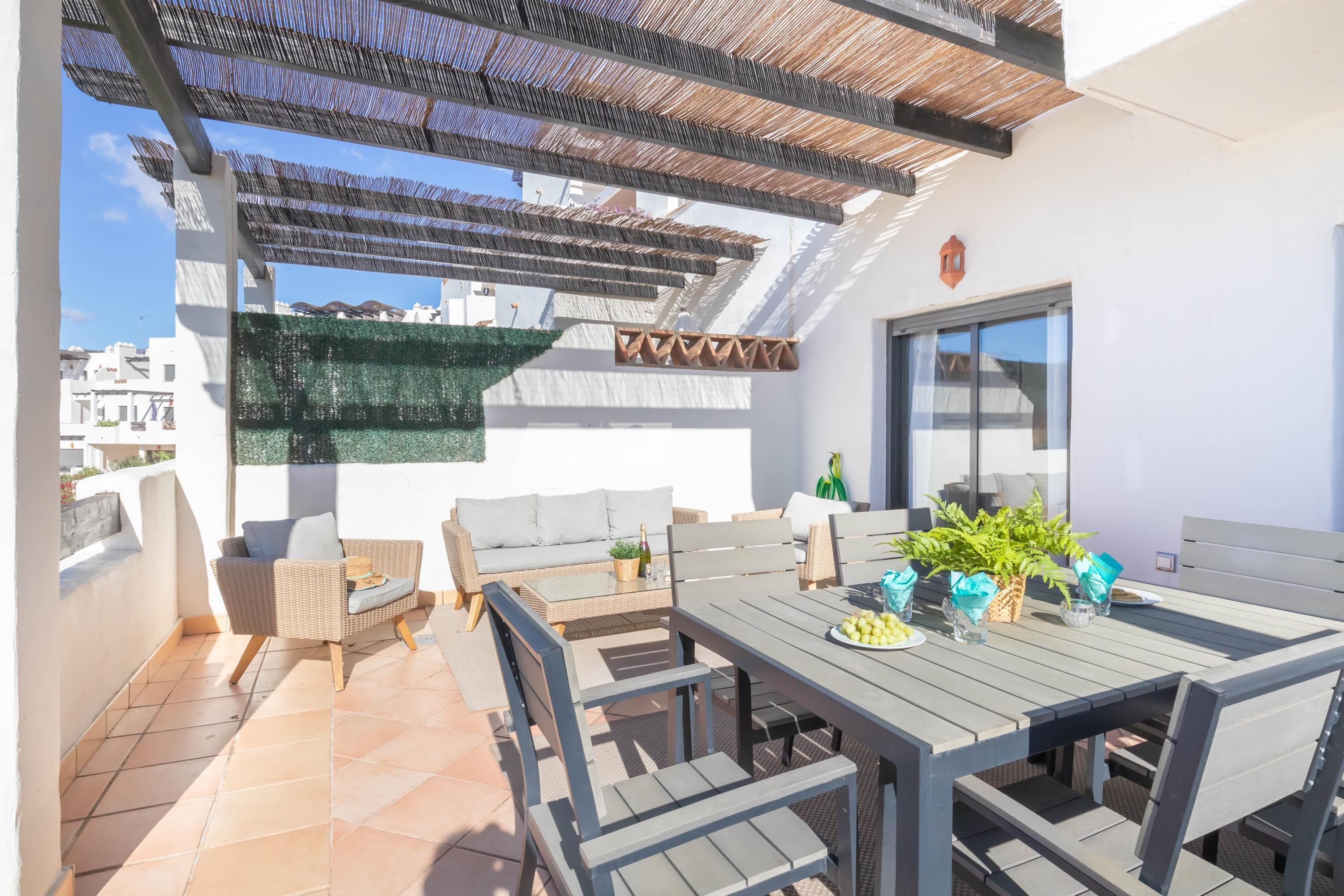 A rooftop terrace with a dining table, chairs, and a sofa.